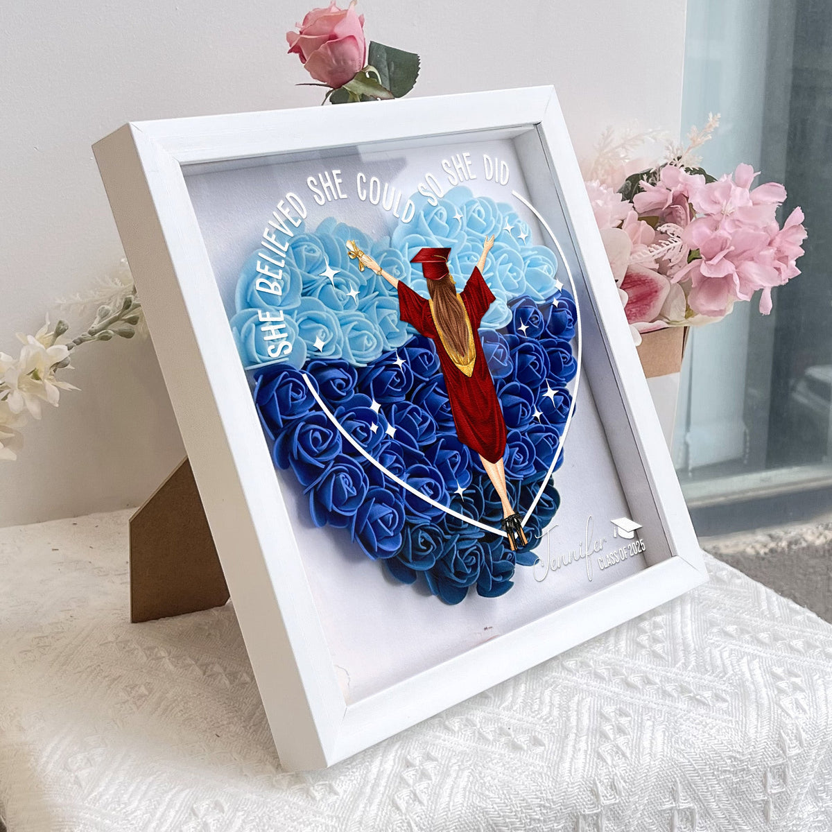 Graduation flower shadow box, heart-shaped design with 'She believed she could so she did' message, in white MDF frame.